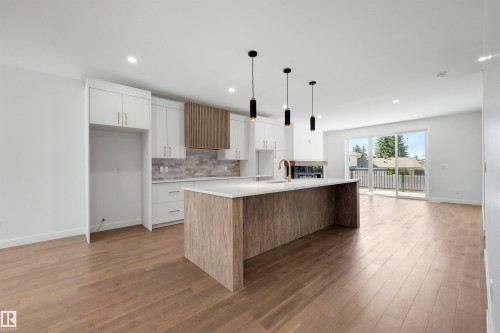 Modern kitchen featuring a central island with a wood-finish base, integrated sink, and gold-tone faucet - 39 Elsinore Place, Edmonton, AB 