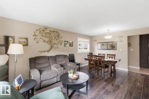 Open-concept living and dining area featuring wood-finish flooring, neutral wall tones, and a dining space with a chandelier - 4007 45 Street, Stony Plain, AB 