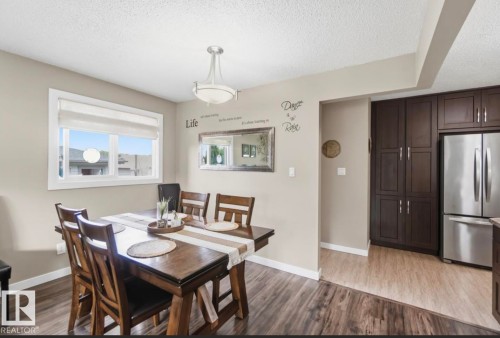 Dining area featuring wood-finish flooring, a white trim window, and a contemporary ceiling fixture - 4007 45 Street, Stony Plain, AB 