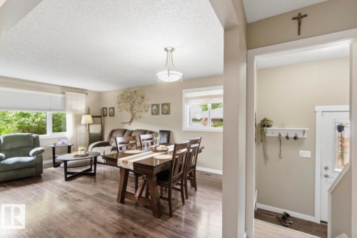 Spacious living area featuring wood-finish flooring, multiple windows, and a ceiling-mounted light fixture - 4007 45 Street, Stony Plain, AB 