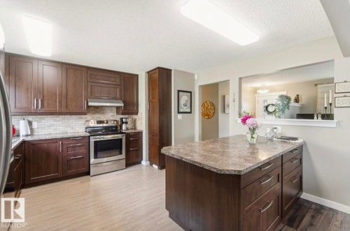 Kitchen featuring dark wood cabinetry, light-toned countertops, and a subway tile backsplash - 4007 45 Street, Stony Plain, AB 