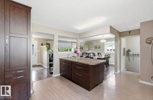 Kitchen featuring a central island with a stone-finish countertop, dark wood-finish cabinetry, and light wood-finish flooring - 4007 45 Street, Stony Plain, AB 