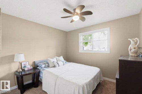 Neutral-toned interior with a ceiling fan, a window with white trim, and light brown carpeting - 4007 45 Street, Stony Plain, AB 