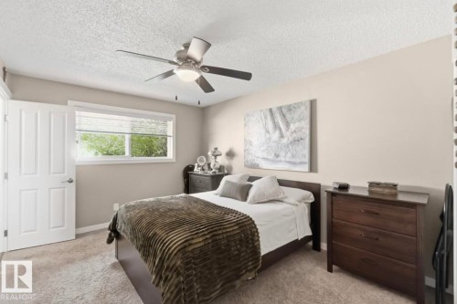 Carpeted bedroom with neutral-toned walls, a white window with blinds, and a ceiling fan with light fixture - 4007 45 Street, Stony Plain, AB 