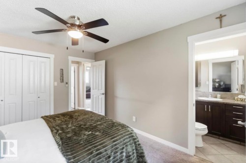 Bedroom featuring a ceiling fan with integrated lighting, dual bi-fold closet doors, and light-toned carpet flooring - 4007 45 Street, Stony Plain, AB 