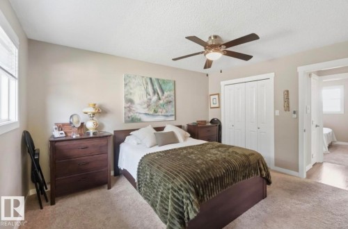 Carpeted room featuring a ceiling fan with integrated lighting, a double-door closet with white bi-fold doors, and a window with blinds - 4007 45 Street, Stony Plain, AB 
