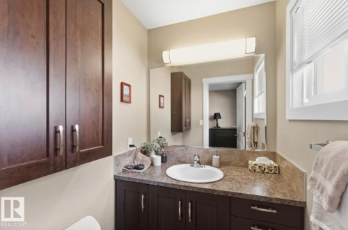 Bathroom featuring dark wood-finish cabinetry, a white oval sink, and a speckled countertop - 4007 45 Street, Stony Plain, AB 