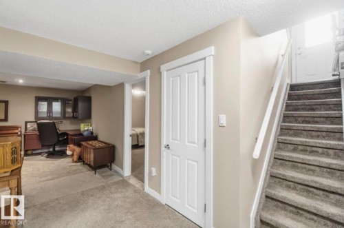 Carpeted staircase with white handrail and a closed white paneled door - 4007 45 Street, Stony Plain, AB 
