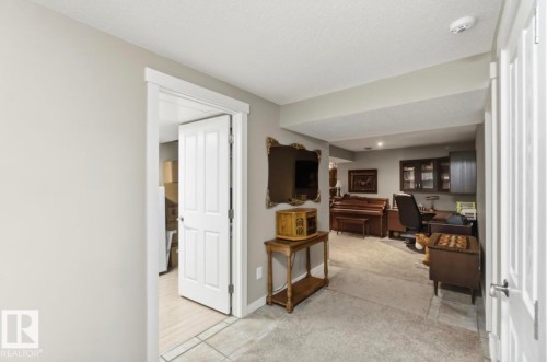 Carpeted room with a built-in dark wood desk and glass-front cabinetry - 4007 45 Street, Stony Plain, AB 