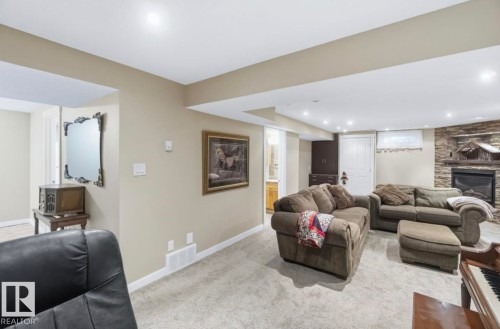 Spacious finished basement featuring recessed lighting, light-toned carpeting, neutral wall paint, and a stone-clad fireplace - 4007 45 Street, Stony Plain, AB 
