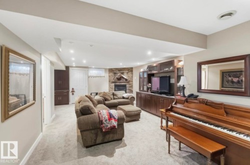 Living area featuring recessed lighting, a stone-accented fireplace, and a built-in media console with dark wood cabinetry - 4007 45 Street, Stony Plain, AB 