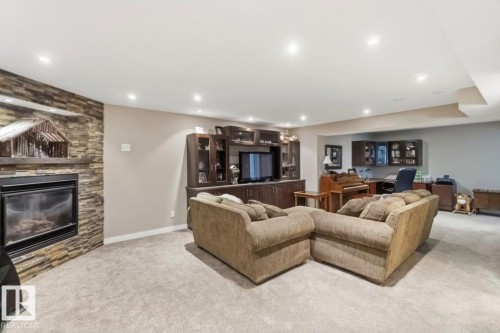 Spacious living area featuring a stacked stone fireplace, recessed lighting, wall-to-wall carpeting, custom built-in cabinetry, and a dedicated desk area with overhead storage - 4007 45 Street, Stony Plain, AB 