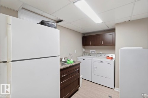 Dedicated utility space featuring a laundry sink, wood-finish cabinetry, and a drop ceiling with integrated lighting - 4007 45 Street, Stony Plain, AB 