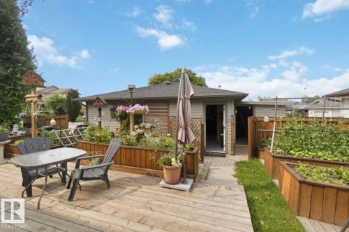 Expansive outdoor living area featuring a wooden deck, stone pathway, and raised garden beds - 4007 45 Street, Stony Plain, AB 