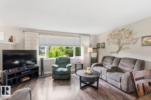 Spacious living area featuring wood-finish flooring, neutral wall tones, and a large window providing abundant natural light - 4007 45 Street, Stony Plain, AB 