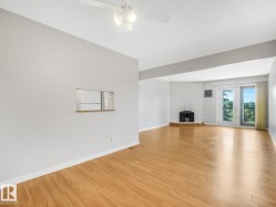 Bright interior showcasing wood-finish flooring, a white brick fireplace, and double glass doors - 