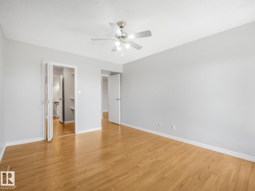 Spacious room featuring wood-finish flooring, light gray walls, and a ceiling fan with integrated lighting - 301 10528 29 Avenue, Edmonton, AB 