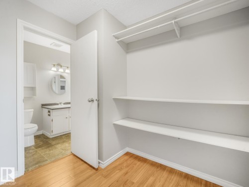 Hardwood-finish flooring extending into a spacious closet with built-in shelving and hanging rod - 301 10528 29 Avenue, Edmonton, AB 