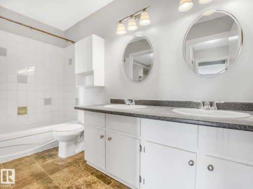 Bathroom featuring a dual-sink vanity with a dark countertop and white cabinetry - 301 10528 29 Avenue, Edmonton, AB 