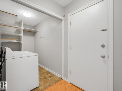 Entryway with a white door, chrome hardware, and wood-finish flooring - 301 10528 29 Avenue, Edmonton, AB 