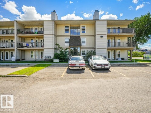 Multi-story residential building featuring balconies with black railings, tan siding, and a gabled entrance - 301 10528 29 Avenue, Edmonton, AB 