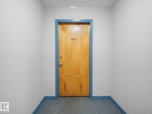 Light wood-finish door with blue trim and contrasting white walls - 301 10528 29 Avenue, Edmonton, AB 