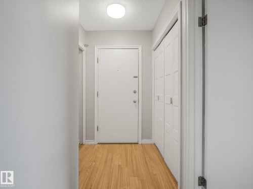 Entryway featuring wood-finish flooring, a flush-mount ceiling light, white paneled doors, and bi-fold closet doors - 301 10528 29 Avenue, Edmonton, AB 