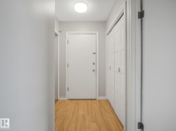 Entryway featuring wood-finish flooring, a flush-mount ceiling light, white paneled doors, and bi-fold closet doors - 