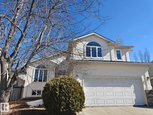 Stucco exterior featuring a two-car garage, arch-top windows, and a gabled roofline - 1641 Forbes Way, Edmonton, AB - Outdoor
