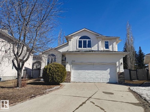 Two-story stucco residence featuring an attached double garage, an arched window, and a concrete driveway - 1641 Forbes Way, Edmonton, AB - Outdoor