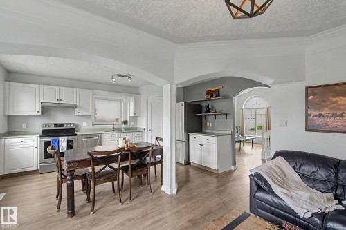 Open-concept kitchen and dining area featuring white cabinetry, stainless steel appliances, and light wood-finish flooring - 1619 Welbourn Cove, Edmonton, AB 