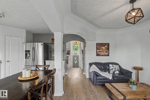 Open-concept living area featuring wood-finish flooring, crown molding, an arched entryway, and recessed lighting - 1619 Welbourn Cove, Edmonton, AB 