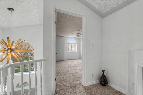 Upper-level area featuring plush carpeting, a vaulted ceiling, and an arched window - 1619 Welbourn Cove, Edmonton, AB 