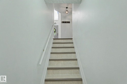 Staircase featuring light-toned treads, white risers, and a white handrail - 1619 Welbourn Cove, Edmonton, AB 
