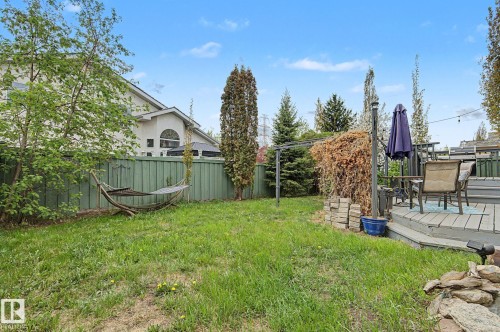 Expansive green space featuring a multi-level wood deck, privacy fencing, mature trees, and a stone-edged garden area - 1619 Welbourn Cove, Edmonton, AB 