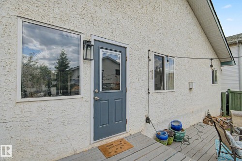 Exterior wall with stucco finish and a contrasting gray door with an upper window pane - 1619 Welbourn Cove, Edmonton, AB 