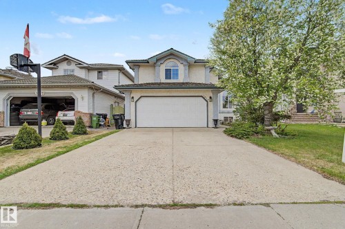 Two-story stucco exterior with a prominent arched window feature, a two-car garage, and a concrete driveway - 1619 Welbourn Cove, Edmonton, AB 