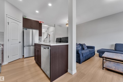 Contemporary kitchen island featuring a stainless steel dishwasher, undermount sink with a gooseneck faucet, and white countertop - 2246 54 Street, Edmonton, AB 