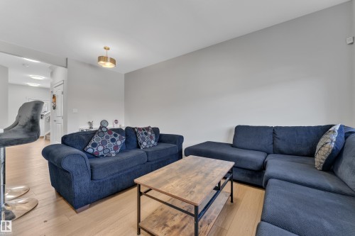 Bright living area featuring light wood-finish flooring, light gray wall paint, and a modern ceiling light fixture - 2246 54 Street, Edmonton, AB 