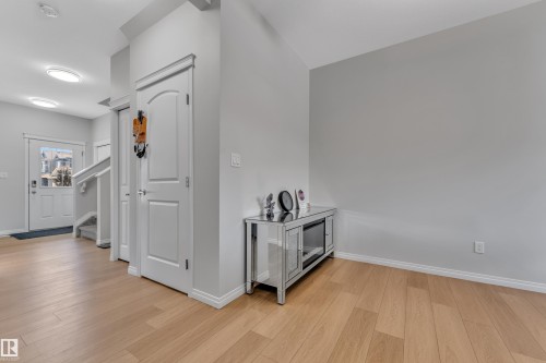 Entryway featuring wood-finish flooring, light grey wall paint, white trim, and a white paneled door - 2246 54 Street, Edmonton, AB 