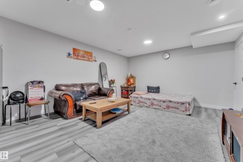 Spacious room featuring light gray walls, recessed lighting, wood-finish flooring, and a large area rug - 2246 54 Street, Edmonton, AB 