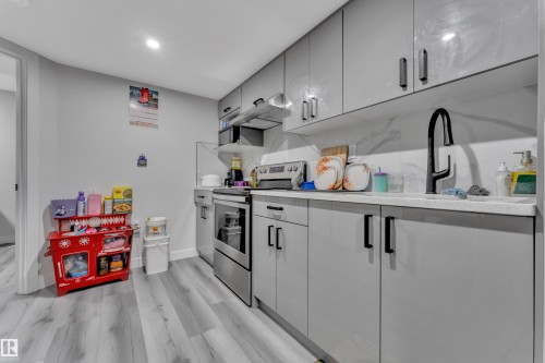 Kitchen featuring light gray cabinetry, white countertops, a black gooseneck faucet, stainless steel appliances, and wood-finish flooring - 2246 54 Street, Edmonton, AB 