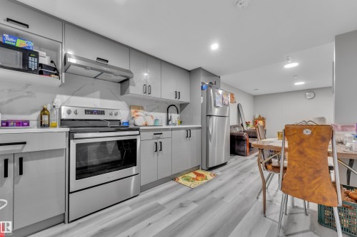 Contemporary kitchen featuring light gray cabinetry, stainless steel appliances, and wood-finish flooring - 2246 54 Street, Edmonton, AB 