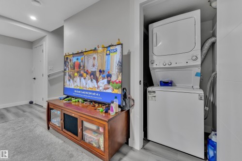 White stacked washer and dryer unit within a dedicated closet space, featuring a metal dryer vent - 2246 54 Street, Edmonton, AB 