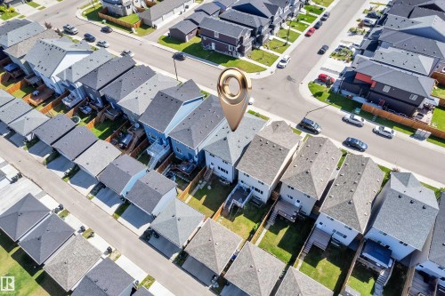 Aerial view of a residential street featuring uniform detached homes with grey shingle roofs and fenced backyards - 2246 54 Street, Edmonton, AB 