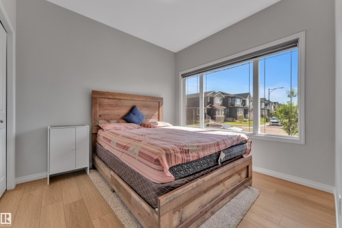 Room featuring wood-finish flooring, a contemporary window with a streetscape, and a white closet door - 2246 54 Street, Edmonton, AB 