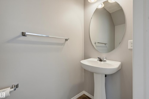 Pedestal sink with chrome faucet, complemented by an oval mirror and overhead vanity lighting - 126 2051 Towne Centre Boulevard, Edmonton, AB 