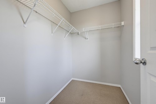 Spacious walk-in closet featuring wire shelving, built-in clothing rods, and neutral-toned carpeting - 126 2051 Towne Centre Boulevard, Edmonton, AB 