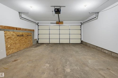 Spacious garage featuring a concrete floor, white painted walls, and an automatic garage door opener - 126 2051 Towne Centre Boulevard, Edmonton, AB 