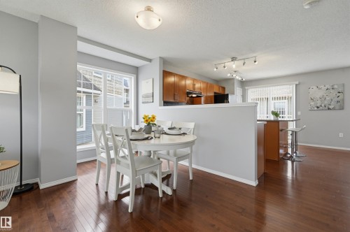 Open-concept dining area featuring wood-finish flooring, a contemporary ceiling light fixture, and a large window - 126 2051 Towne Centre Boulevard, Edmonton, AB 